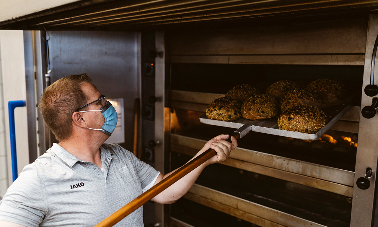 Bäcker mit Brötchen in der Conditorei Kraume